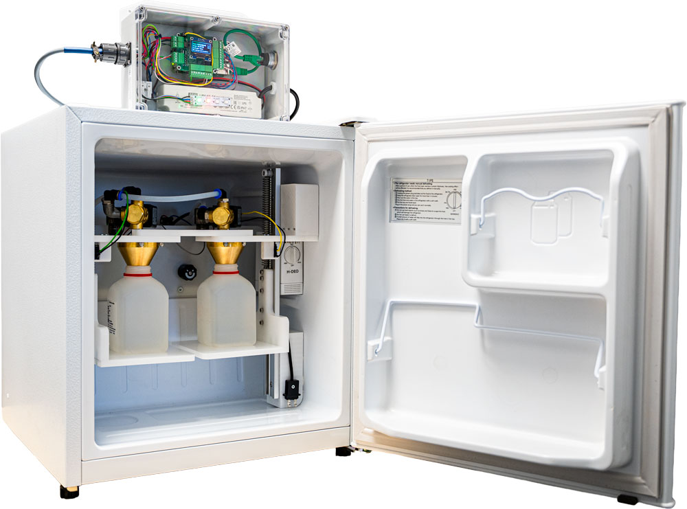 Aqua Alarm autosampler unit, door open, showing sample bottles, valves, and the sensor electronics enclosure mounted on top